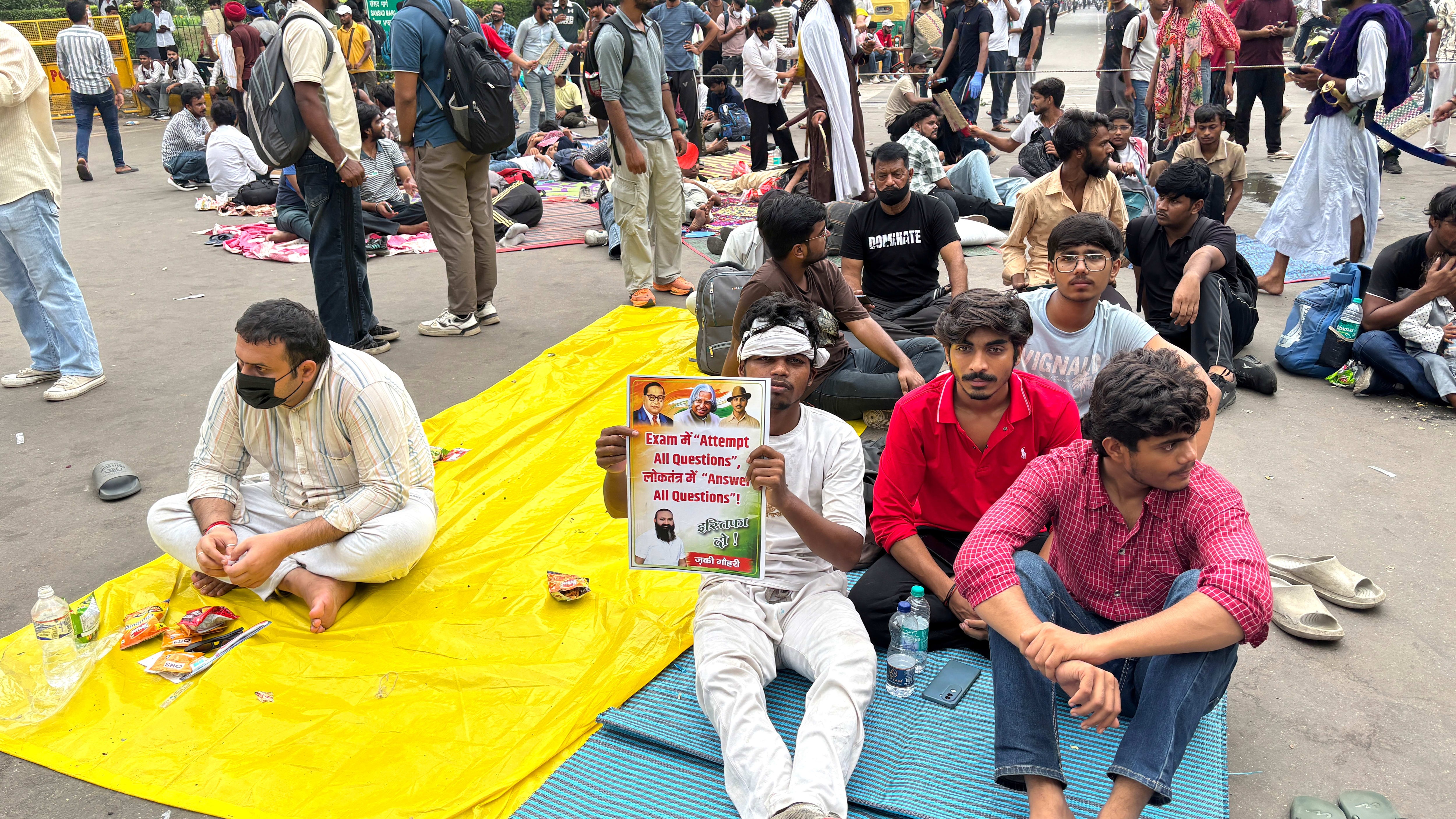 A protestor sits among a group holding a placard calling for educational reforms during a demonstration in New Delhi.