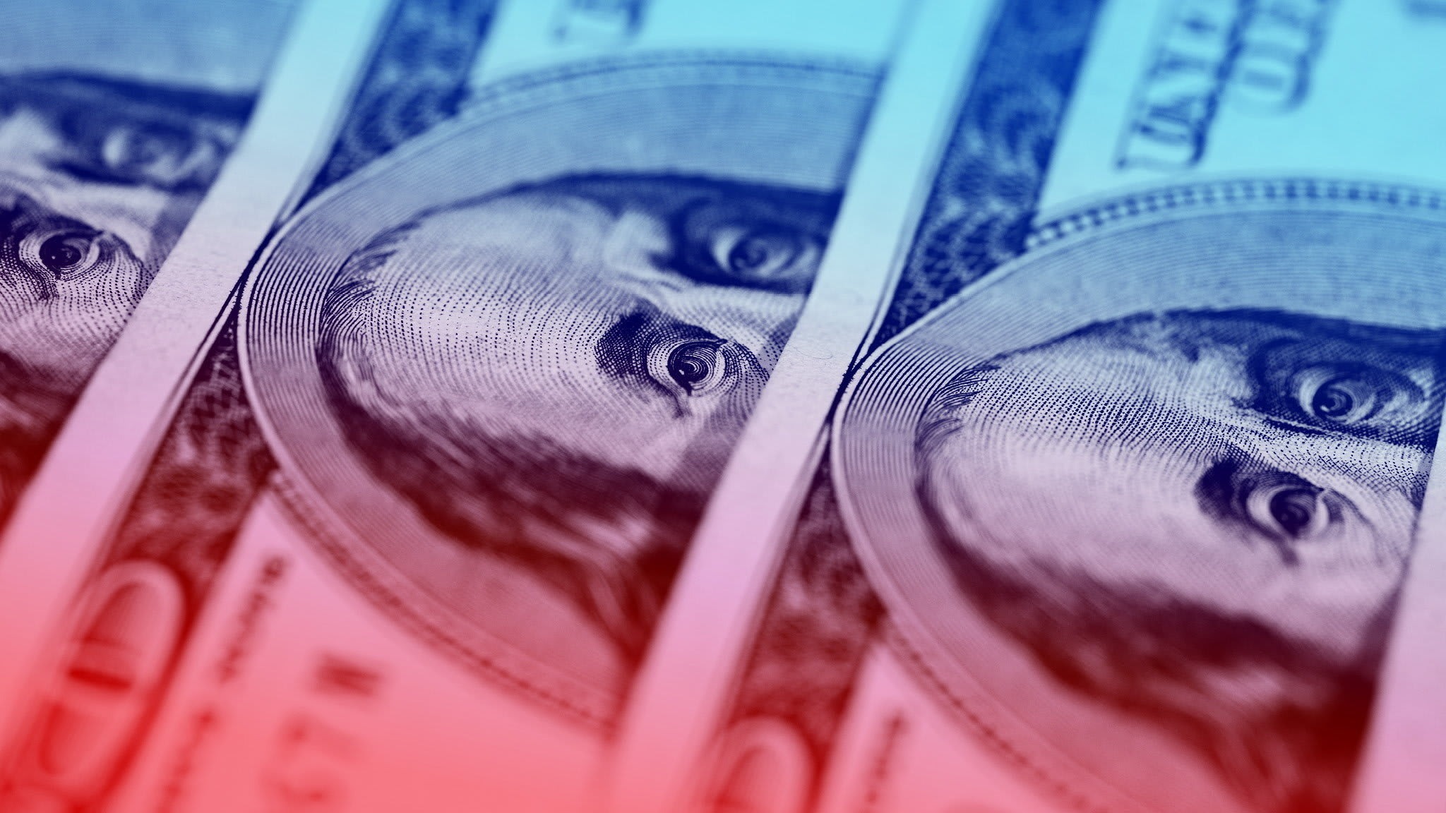 Close-up of multiple U.S. $100 bills showing Benjamin Franklin’s eyes, with a blue and red colour overlay.